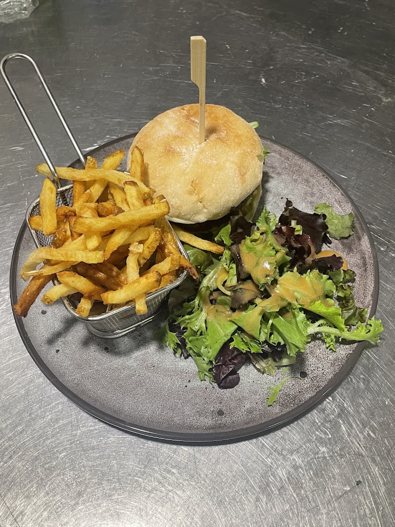 Un burger servi avec des frites et une salade